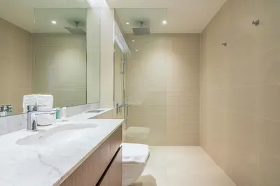 a bathroom with a sink and a toilet and a mirror at Cozy 3BR Sea-View Apartment in La Rive 1 in Dubai