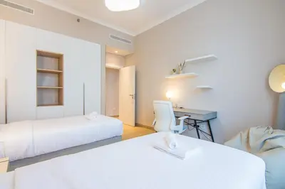 a hotel room with two beds and a desk at Cozy 3BR Sea-View Apartment in La Rive 1 in Dubai