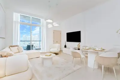 a living room with white furniture and a large window at Elegant 1BR Apartment with Partial Sea View by EE holiday homes in Dubai