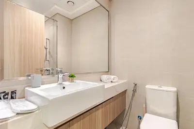a bathroom with a sink and a toilet and a mirror at Greige & Spacious Studio in Dubai