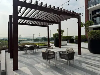 a wooden pergola with tables and chairs on a patio at Greige & Spacious Studio in Dubai