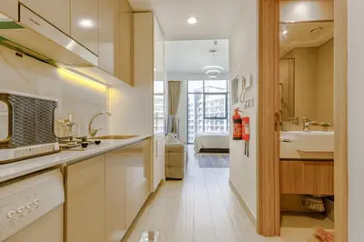 a white kitchen with a sink and a bathroom at Greige & Spacious Studio in Dubai