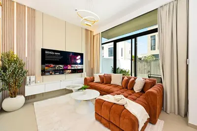 a living room with a large couch and a tv at Golden Stays - Elegant 4BR I Santorini-Style I Sunsets & Comfort in Dubai