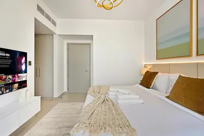 a white bedroom with a white bed and a tv at Golden Stays - Elegant 4BR I Santorini-Style I Sunsets & Comfort in Dubai