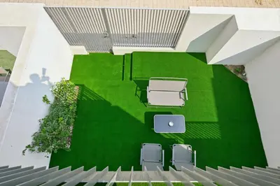 an overhead view of a green lawn with chairs and tables at Golden Stays - Elegant 4BR I Santorini-Style I Sunsets & Comfort in Dubai