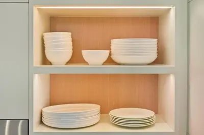 a cabinet filled with white plates and bowls at Golden Stays - Stylish 4BR Villa I Garden, Pool & Parking I Global Village in Dubai