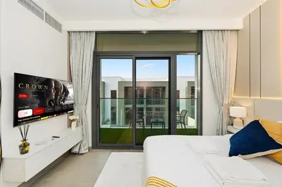 a bedroom with a bed and a tv and a balcony at Golden Stays - Stylish 4BR Villa I Garden, Pool & Parking I Global Village in Dubai