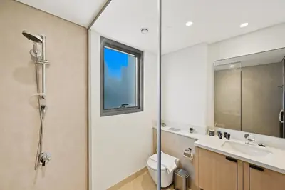 a bathroom with a shower and a toilet and a sink at Golden Stays - Stylish 4BR Villa I Garden, Pool & Parking I Global Village in Dubai