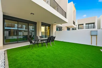 a patio with a table and chairs on a lawn at Golden Stays - Chic 4BR Retreat I Luxe Touches & Serene Views in Dubai