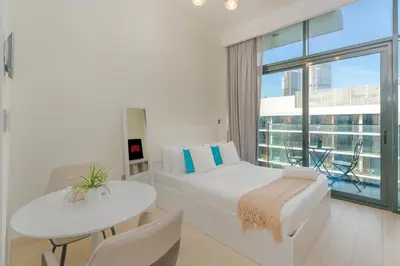 a bedroom with a bed and a table and a window at Chic Urban Studio l Poolside Living l Balcony in Dubai