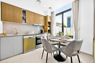 a kitchen with a table and chairs and a sink at Golden Stays - Tranquil 4BR Villa I Pool & Coastal Charm in Dubai