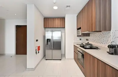a kitchen with a stainless steel refrigerator and wooden cabinets at Golden Stays - Palm Views I Luxe 4BR Getaway I Tranquil Charm in Dubai