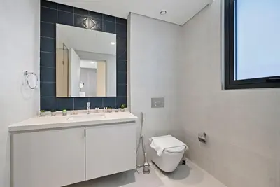 a bathroom with a toilet and a sink and a mirror at Golden Stays - Italian Riviera 4BR Villa I Stylish Bliss Living in Dubai