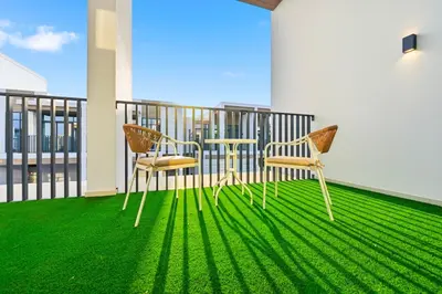 two chairs and a table on a balcony with green grass at Golden Stays - Italian Riviera 4BR Villa I Stylish Bliss Living in Dubai