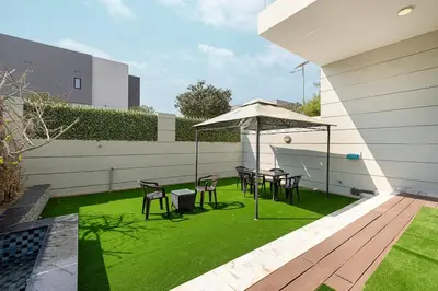 a patio with chairs and an umbrella and grass at Modern 4Bedroom Villa in Al Furjan in Dubai