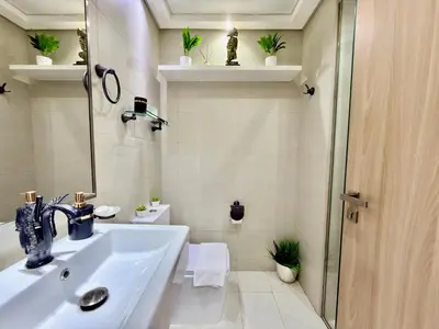 a white bathroom with a sink and a shower at Luxury Stay in Meydan - 10min to Downtown in Dubai