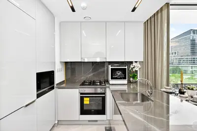 a white kitchen with a stove and a sink at Golden Stays - Luxe 1BR Retreat I Cinema Access & Elegant Stay in Dubai