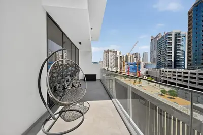 a balcony with a bench and a view of a city at Golden Stays - Luxe 1BR Retreat I Cinema Access & Elegant Stay in Dubai