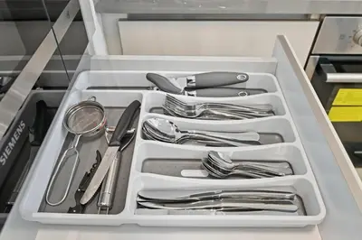 a white drawer filled with utensils in a kitchen at Golden Stays - Luxury 1BR Apartment I Cinema Access I Pool & Gym in Dubai