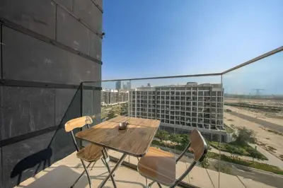 a table and chairs on a balcony with a view of a building at StayShort - Studio Apartment at Azizi Riviera with Balcony in Dubai