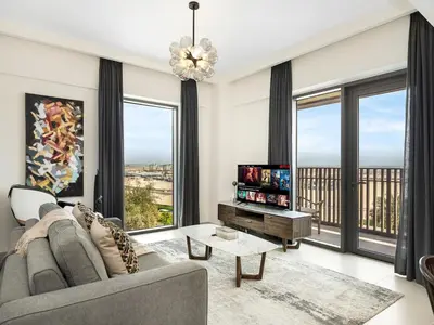 a living room with a couch and large windows at Stylish Dubai Stay 1BR, Lagoon, Pool, Gym in Dubai