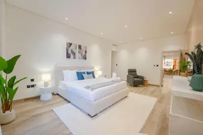 a white bedroom with a large bed and a living room at EasyGo - Luxury 3BR with Maid's Room, Dubai Eye View, JBR in Dubai