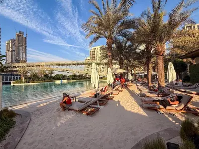 a beach with lounge chairs and palm trees and a bridge at GuestReady - 1BR | Creek Beach Getaway in Dubai