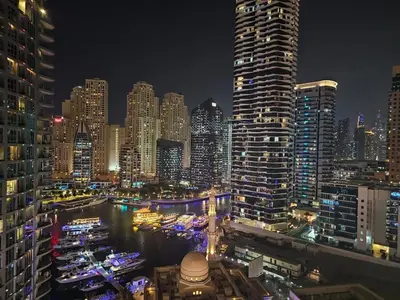 a city skyline at night with boats in the water at Marina View Apartment Near JBR Beach & Marina Mall in Dubai