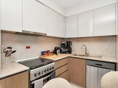 a kitchen with white cabinets and a stove and a sink at New-Best Burj Khalifa View I 2BR I Walk DubaiMall in Dubai