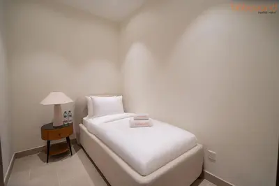 a white bed in a room with a side table at 3BR Skyline Burj Panorama with Infinity Pool Vibes in Dubai