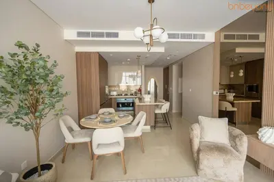 a living room with a table and chairs and a kitchen at 3BR Skyline Burj Panorama with Infinity Pool Vibes in Dubai