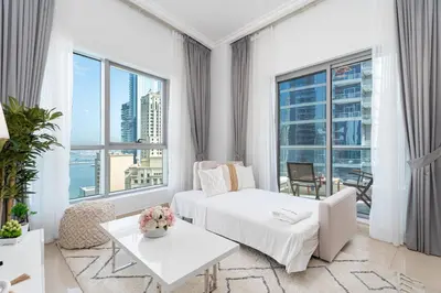 a white living room with a bed and a table at Gala Guests - Luxury Dubai Marina View Apartments - 1 min Walk to Tram in Dubai