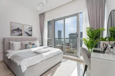 a white bedroom with a bed and a large window at Gala Guests - Luxury Dubai Marina View Apartments - 1 min Walk to Tram in Dubai