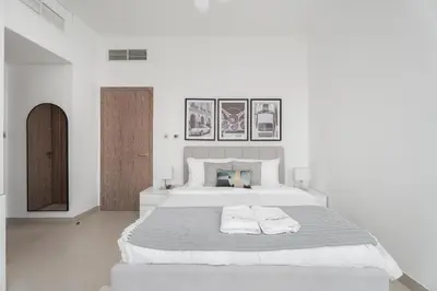 a white bedroom with a large bed with two towels at Gala Guests - LIV Contemporary Marina View Apartment Collection in Dubai
