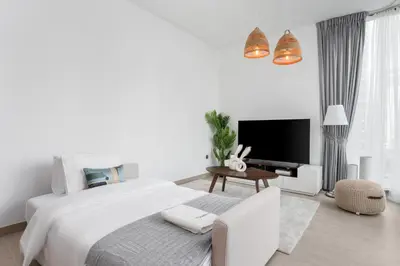 a white bedroom with a large bed and a tv at Gala Guests - LIV Contemporary Marina View Apartment Collection in Dubai