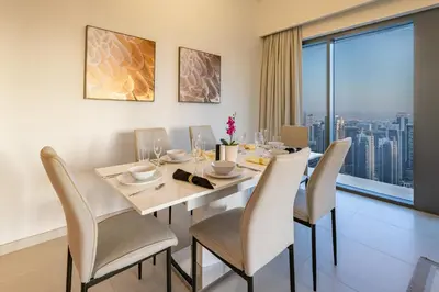 a dining room with a table and chairs and a large window at Burj Royale Luxury 3BR Apartment in Dubai