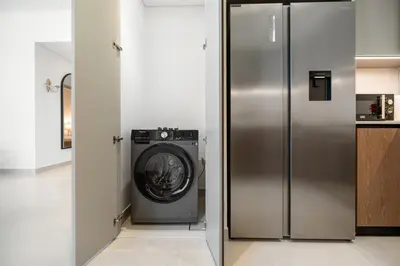 a stainless steel refrigerator in a kitchen with a washing machine at BLVD-Manhattan Vibes 4BR High Floor Creek in Dubai