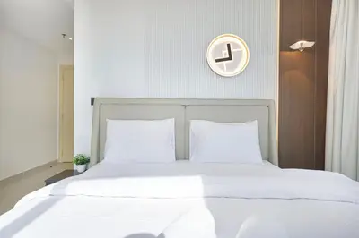 a bed with white sheets and a clock on the wall at Luxury 3 BHK in Dubai Marina DEC 1402 T2 in Dubai