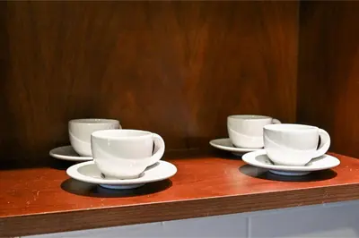 four white cups and saucers on a wooden counter at Luxury 1BR, Long Stays & Walk to Burj Khalifa, High Speed Internet in Dubai