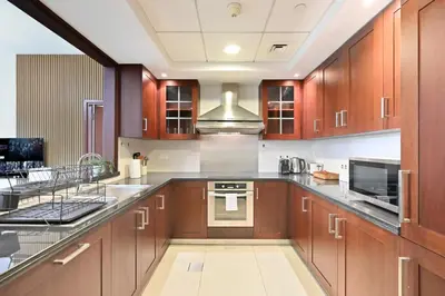 a large kitchen with wooden cabinets and stainless steel appliances at Luxury 1BR, Long Stays & Walk to Burj Khalifa, High Speed Internet in Dubai