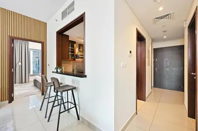 a kitchen and living room with a bar and stools at Luxury 1BR, Long Stays & Walk to Burj Khalifa, High Speed Internet in Dubai