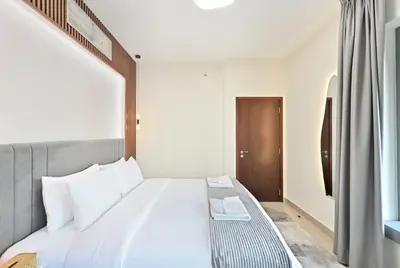 a bedroom with a white bed with a wooden headboard at Luxury 1BR, Long Stays & Walk to Burj Khalifa, High Speed Internet in Dubai