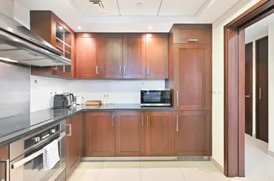 a kitchen with wooden cabinets and a microwave at Luxury 1BR, Long Stays & Walk to Burj Khalifa, High Speed Internet in Dubai