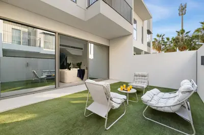 a patio with white chairs and a table on a green rug at Family 4BR Villa | PS5 & Garden | New Community in Dubai