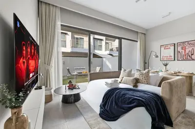 a living room with a couch and a tv at Family 4BR Villa | PS5 & Garden | New Community in Dubai