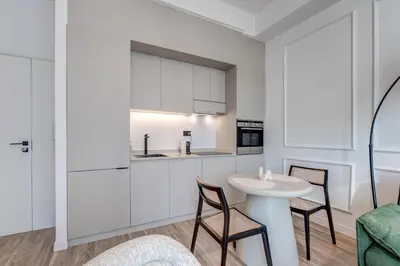 a kitchen with white cabinets and a table and chairs at Urban Chic 1Bedroom in DEC Tower Marina in Dubai