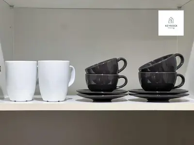 three black and white cups sitting on a shelf at Modern 1-Bedroom Luxury Stay with Lake View in Reva, Business Bay in Dubai