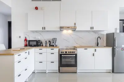 a white kitchen with white cabinets and appliances at Luxury 3 BR in Dubai Marina By dPie DEC T1 503 in Dubai