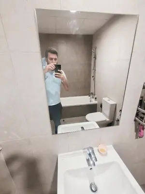 a man taking a picture of himself in a bathroom mirror at Private Room with Bath in Dubai