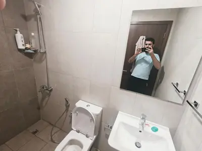 a man taking a picture of a bathroom mirror at Private Room with Bath in Dubai